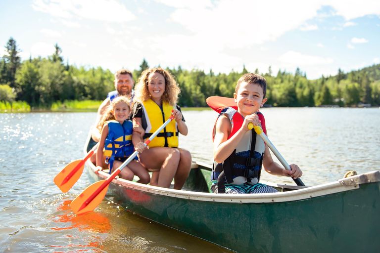 Adults and kids in a canoe while wearing lifejackets, canoe lifejacket concept.