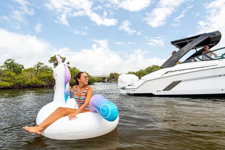Girl on inflatable unicorn on water near boat, New York watercraft laws concept. 